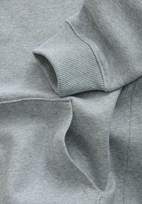 Helehall sweatshirt kangas, millel on soonik ja esiküljel kanavakott, nähtavate õmbluste ja tekstuuriga.