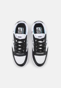 Svarta och vita sneakers med en överdel av läder och canvas, med rund tå, svarta snörning och en Vans-logotyp på tungan.