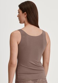 Top senza maniche marrone con scollatura rotonda e texture liscia, realizzato in un tessuto elastico, con design aderente.