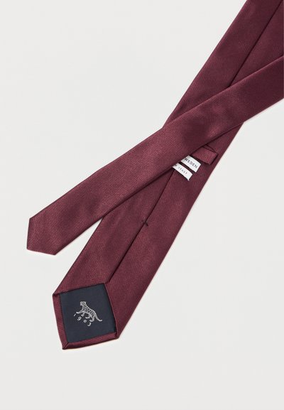 Cravatta bordeaux con finitura testurizzata, dotata di una fodera nera con logo di tigre bianca e etichette del marchio. Design della punta triangolare.