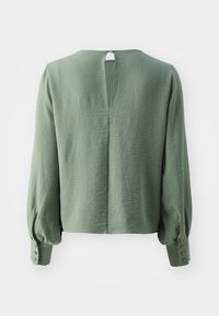 Blusa verde texturizada con mangas largas abullonadas, abertura en la espalda con forma de llave y detalle de botón en el puño. Ajuste casual y relajado con dobladillo redondeado.