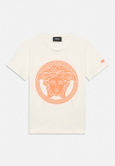 T-shirt blanc à manches courtes avec un grand motif tête de Méduse orange centré sur le devant et une petite étiquette orange sur la manche.