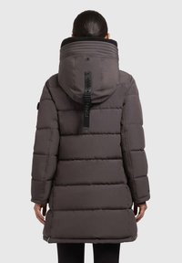 Parka gris acolchada con una gran capucha, cuello acanalado y tira de logo negro. Presenta secciones acolchadas horizontales y bolsillos laterales.