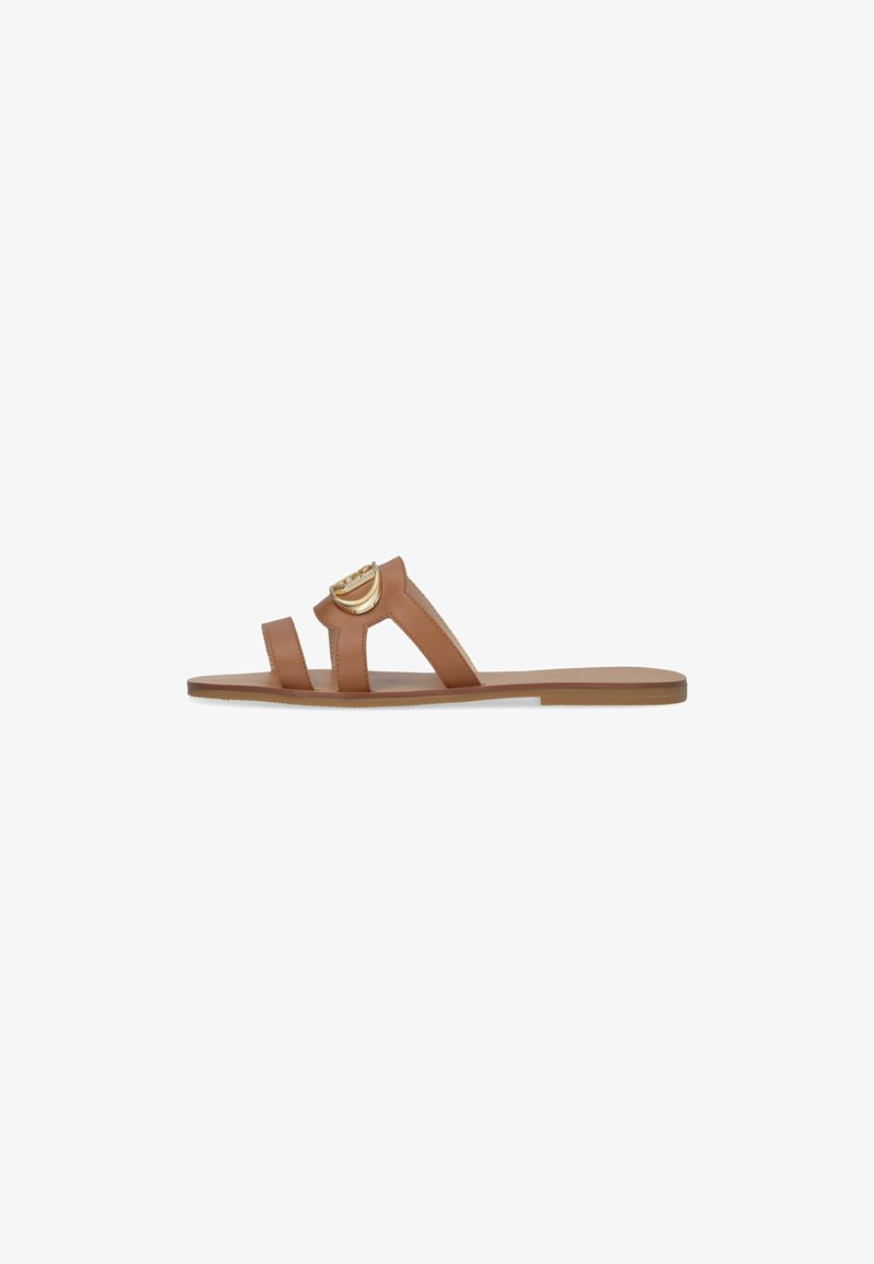 I sandali slide in pelle marrone chiaro presentano due ampie cinghie con un accento circolare dorato, suola piatta e superficie liscia.