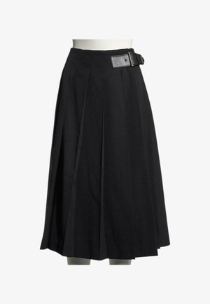 Jupe plissée noire longueur genou avec une large ceinture et une grande boucle rectangulaire sur le côté droit, présentée sur un buste de mannequin blanc.