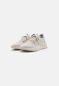 Light grey sneakers with a mesh upper, rounded toe, thin laces, and a textured rubber sole. Includes grey accents on the heel.