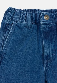 Modri jeans z elastičnim pasom, sprednjimi žepi in gumbom za zapiranje. Material ima teksturiran zaključek z vidnimi šivi.