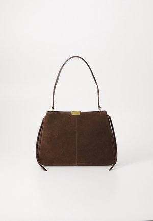 Bruine suède handtas met enkele schouderriem, goudkleurige logoplaat en slanke tassel-details aan de zijkant op een lichte achtergrond.