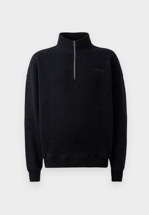 Suéter negro con un alto cuello y cremallera de cuarto, hecho de una tela suave. Presenta puños acanalados y un logo sutil en el pecho.