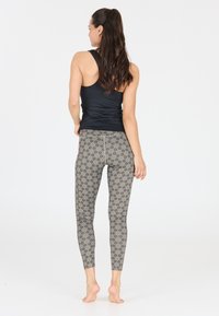 Zwarte tanktop en grijze legging met een patroon in bloemdesign, aansluitende pasvorm, zachte textuur en enkel-lange snit, gezien vanaf de achterkant.