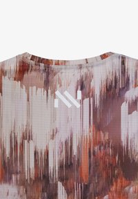 Close-up van de achterkant van een overhemd met een abstract patroon in bruine en beige tinten, met een wit geometrisch logo vlak bij de halslijn.