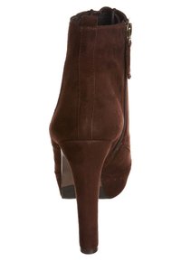 Botín de ante marrón con tacón de aguja estrecho, cierre de cremallera en el lateral y textura suave. Diseño clásico, sin patrones ni detalles adicionales.