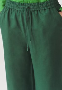Groene relaxte broek met een elastische tailleband met trekkoord, een gladde textuur en zijzakken.