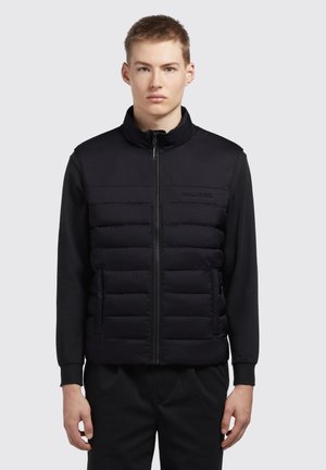 Schwarze ärmellose Puffer-Weste mit einem Frontreißverschluss, ausgestattet mit einer gesteppten Textur und einem hohen Kragen. Glattes Material auf den Schultern und am Rücken.