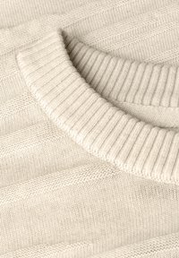 Pull léger beige avec un col rond côtelé. La texture est douce avec un subtil motif en chevrons tout au long.