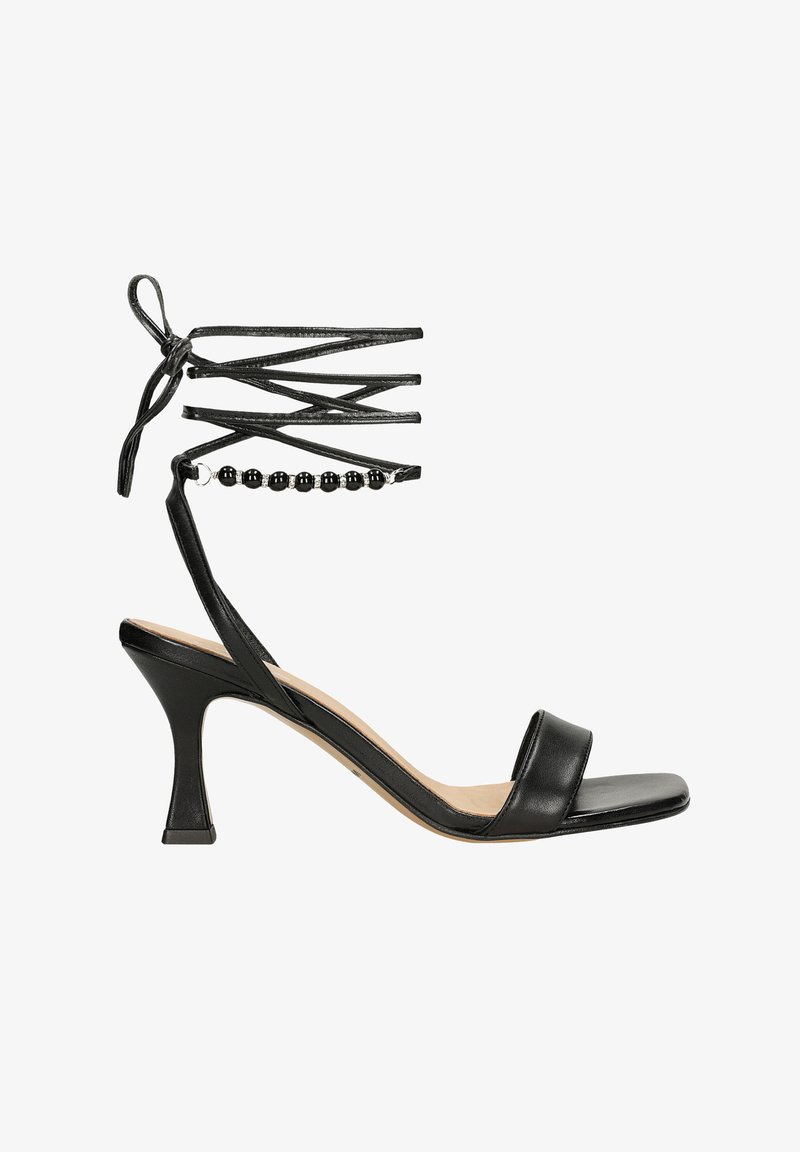 Sandal con tacco alto in pelle nera, con laccetto alla caviglia, dotato di un accento di perline e un design con punta quadrata. Tacco di altezza media, affusolato.