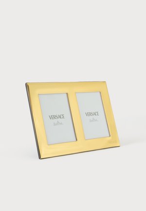 Marco de fotos doble dorado con dos aberturas rectangulares que muestran marcadores de posición de la marca Versace sobre un fondo blanco.