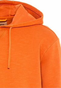 Sweat à capuche orange avec cordons, tissu doux et coutures visibles sur l'épaule et à l'intérieur de la capuche.