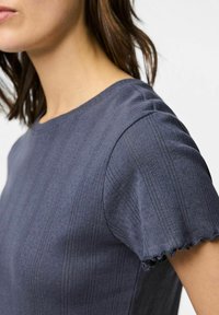 Marinblå texturerad skjorta med korta ärmar, med ett ribbat mönster och något volangiga ärmkanter.