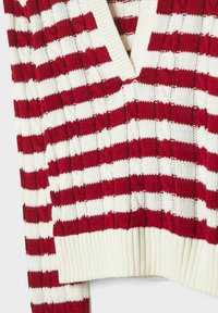 Pull en maille rayé horizontal rouge et blanc avec col en V et ourlets et poignets côtelés.
