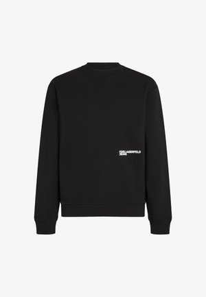 Sweatshirt noir en mélange de coton avec col rond et poignets côtelés. Présente une marque blanche sur le côté gauche près de l'ourlet.