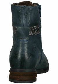 Stivaletto alla caviglia in pelle blu con retro testurizzato, fodera in pelliccia sintetica e tacco impilato. Presenta una cerniera laterale e un nastro decorativo intrecciato.