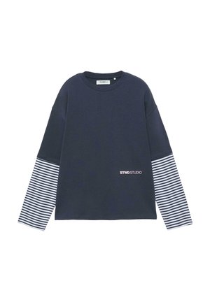 Maglia a maniche lunghe blu mare con maniche inferiori a righe orizzontali bianche e nere e scritta "STWD STUDIO" sul lato anteriore inferiore destro.