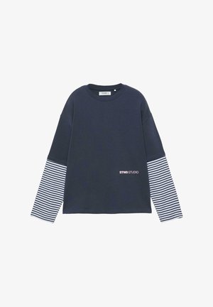 Temno modra majica z dolgimi rokavi, na spodnjem delu rokavov črno-beli vodoravni pasovi in napis "STWD STUDIO" na sprednji spodnji desni strani.