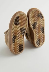 Bottes en velours côtelé beige avec semelles en caoutchouc présentant un motif en zigzag brun, beige et crème. Les semelles montrent des signes d'usure visibles.