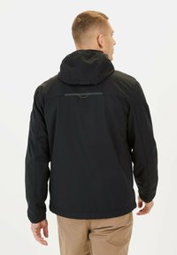 Veste noire imperméable avec capuche, arborant un design épuré, des poignets ajustables et une bande réfléchissante dans le dos.
