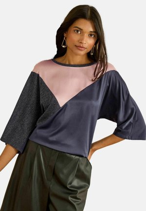 Bluzka w kolorowe bloki z panelami w granatowym, różowym i szarym kolorze. Krótkie, szerokie rękawy o gładkiej teksturze i okrągłym dekolcie.