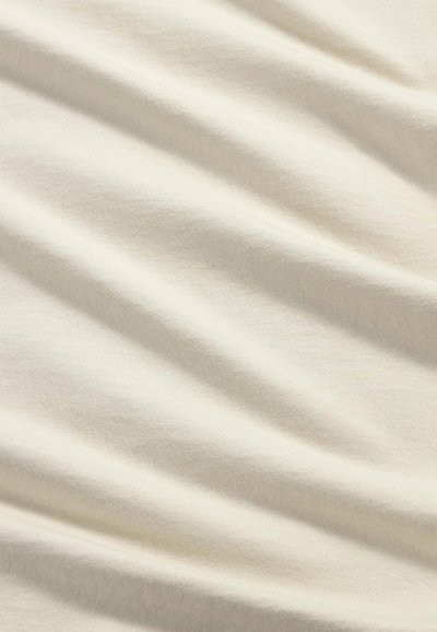 Tessuto color crema con pieghe morbide e dettagli di texture sottili.