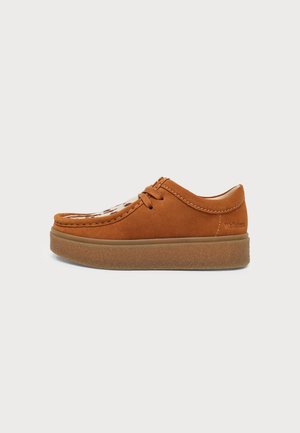 Brown suede casual lace-up shoe with thick rubber sole and light animal print detail on top, side view on a white background.