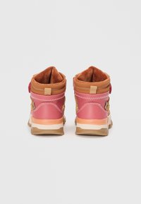 Dwa półwysokie sneakersy z różowym cholewką i brązowymi akcentami, z teksturowanym materiałem i miękką brązową podszewką. Zawierają widoczny uchwyt na pięcie.