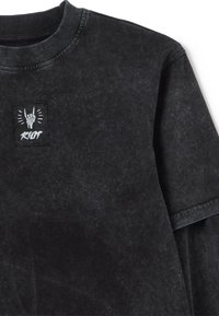 Schwarzer Baumwoll-Sweatshirt mit strukturierter Oberfläche, verfügt über einen Rundhalsausschnitt, kurze Ärmel und ein quadratisches Patch mit einem Handzeichen und dem Text "RIOT".