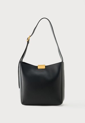 Sac à bandoulière en cuir noir avec sangle réglable et petite boucle rectangulaire dorée sur fond clair.