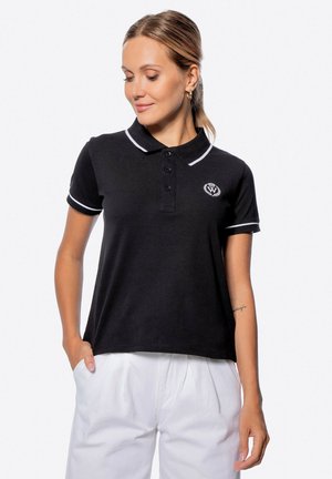 Zwarte polo shirt met witte kraag en mouwaccenten, voorzien van drie knopen en een geborduurd logo op de linkerborst. Katoenen stof.
