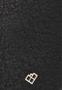 Borsa in pelle nera con texture impresso che presenta piccoli motivi circolari. Accentato da un logo geometrico dorato nell'angolo inferiore.