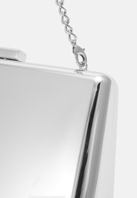 Silverfärgad metallkuvertväska med en slät yta, rektangulär form och en avtagbar kedjesnodd som är fäst med en krabba.