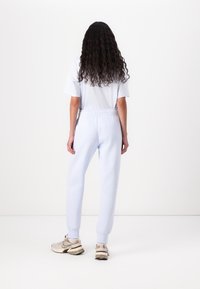 Light blue sweatpants with a relaxed fit, elastic waistband, and cuffed ankles, paired with a loose-fitting white t-shirt.