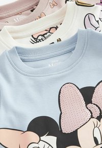 Tre magliette in cotone con motivi Disney. I colori includono blu, bianco e rosa. Dettagli notevoli: un fiocco rosa con paillettes sulla maglietta blu.