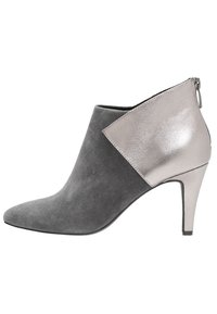 Stivale alla caviglia in suede grigio con punta appuntita, caratterizzato da un accento metallico argentato lucido su un lato e un tacco alto affusolato. Chiusura con cerniera sul retro.