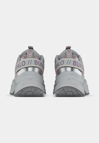 Ζευγάρι λευκά και ασημί chunky sneakers με ροζ λεπτομέρειες, χοντρές σόλες και λογότυπο "BUFFALO" στα λουράκια της φτέρνας και τις σόλες, εμφανίζονται από πίσω.