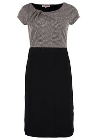 Robe à manches courtes avec jupe noire et haut beige et noir à motifs, présentant de subtils plis près de l'encolure arrondie.