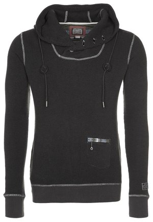 Zwarte waffle-knit hoodie met lange mouwen, trekkoord, hoge kraag, contrasterende stiksels en een klein ritsvakje aan de voorkant aan de linkerkant.