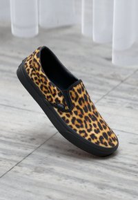 Cipele slip-on s uzorkom leopard kože, izrađene od tkanine s crnom gumom potplata. Imaju niski profil i elastične bočne akcentne detalje za lakše oblačenje.