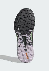 Suola di una scarpa da trail; presenta una suola in gomma nera e verde con tasselli multidirezionali e un intersuola rosa, progettata per garantire aderenza.