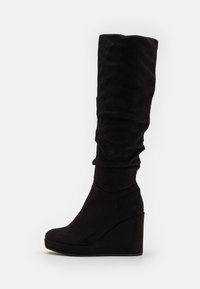 Bottes noires en suede, montantes jusqu'au genou, avec un design décontracté, une texture lisse et un large talon en wedge pour plus de hauteur.