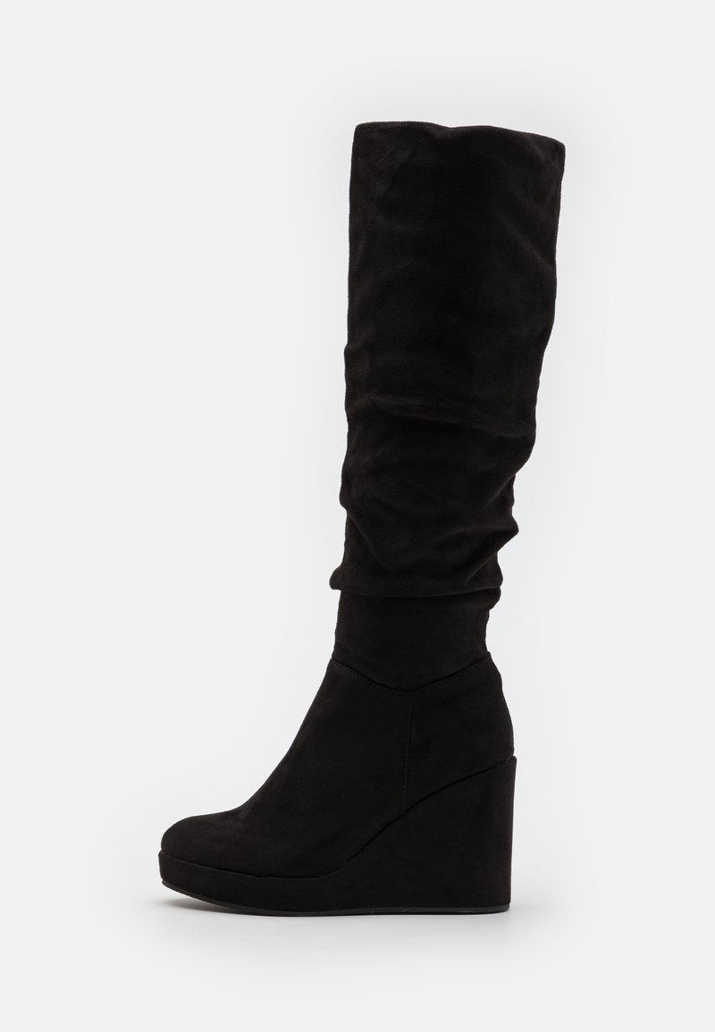 Bottes noires en suede, montantes jusqu'au genou, avec un design décontracté, une texture lisse et un large talon en wedge pour plus de hauteur.
