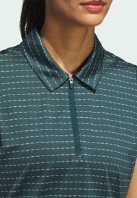Mørk teal polo-shirt med lynlås på fronten, der har en krave og et mønster af tynde vandrette striber i lysere teal. Glat stofstruktur.